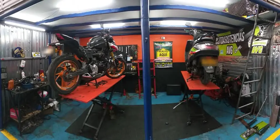 Dos motos sobre los elevadores naranja del taller