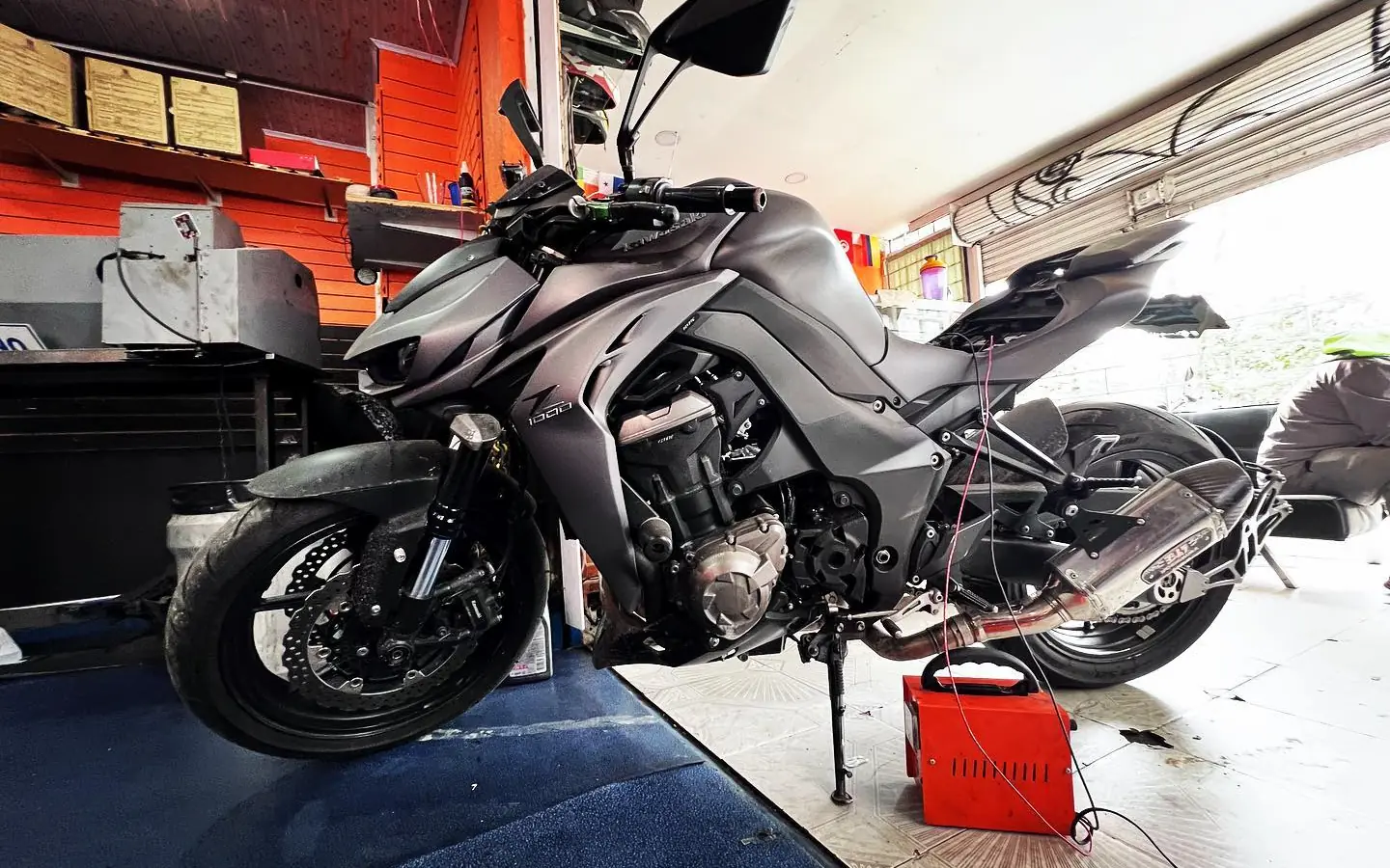 Una moto naked dentro del taller Gorillaz Motorbikes, conectada a un cargador de batería